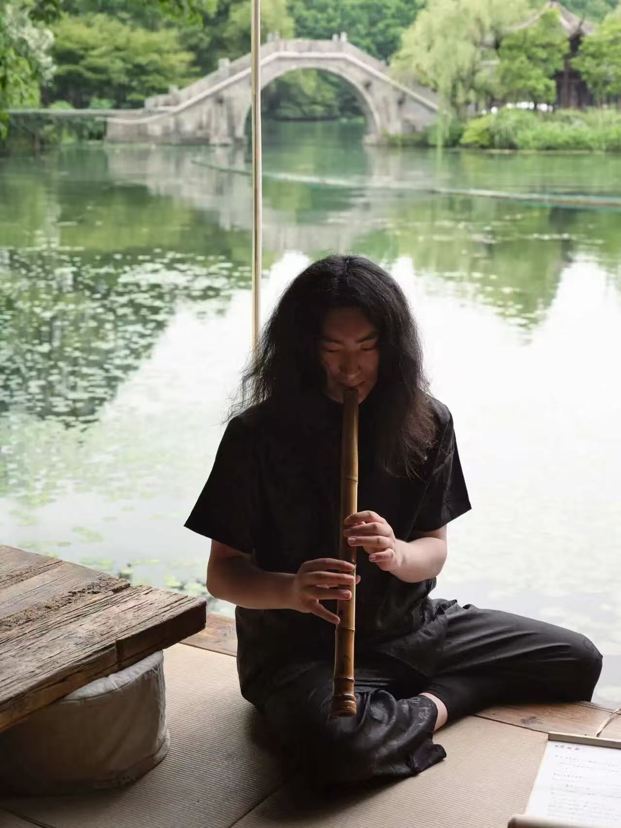 Xiao flutist Gubing playing beside a pond
